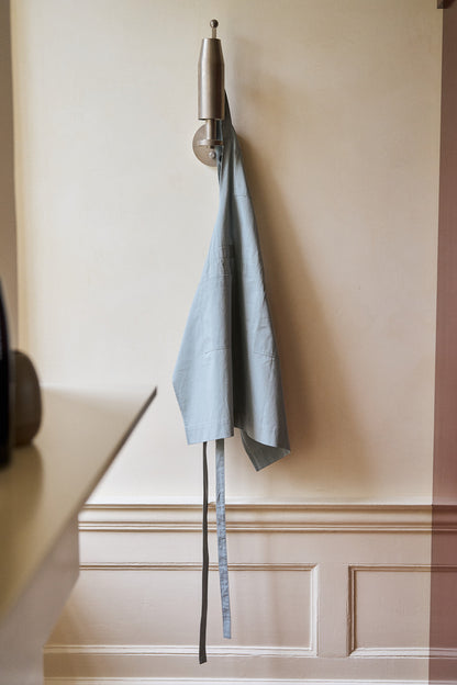 a grey apron hanging on the wall